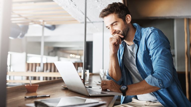 Businessman in a casual setting reading tax updates for Serbia on his laptop.