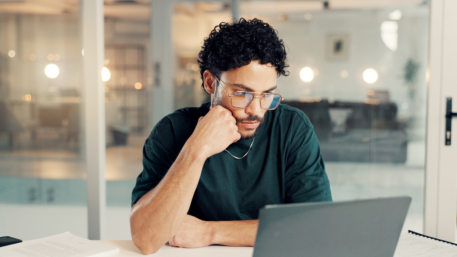 Professional man reading tax news on a laptop in an office environment.