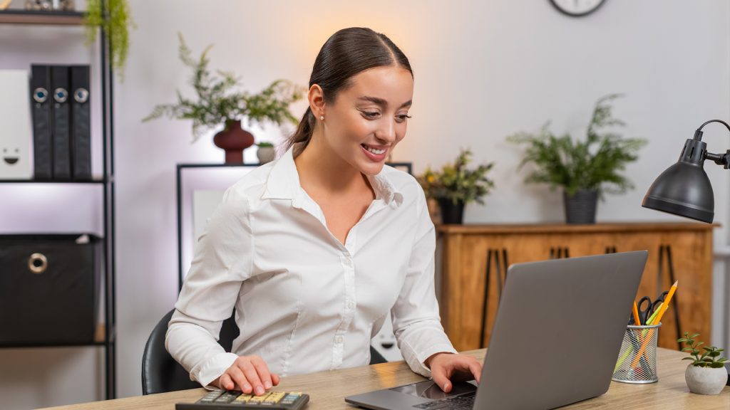 Geschäftsfrau arbeitet am Laptop im Büro und überprüft steuerliche sowie finanzielle Informationen.