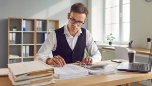 Accounting manager reviewing financial documents and calculations, analyzing reports and ensuring accuracy in financial records.