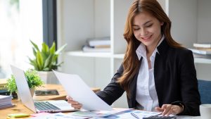 Business professional reviewing financial reports and calculating data at a desk, representing accounting and financial analysis tasks.